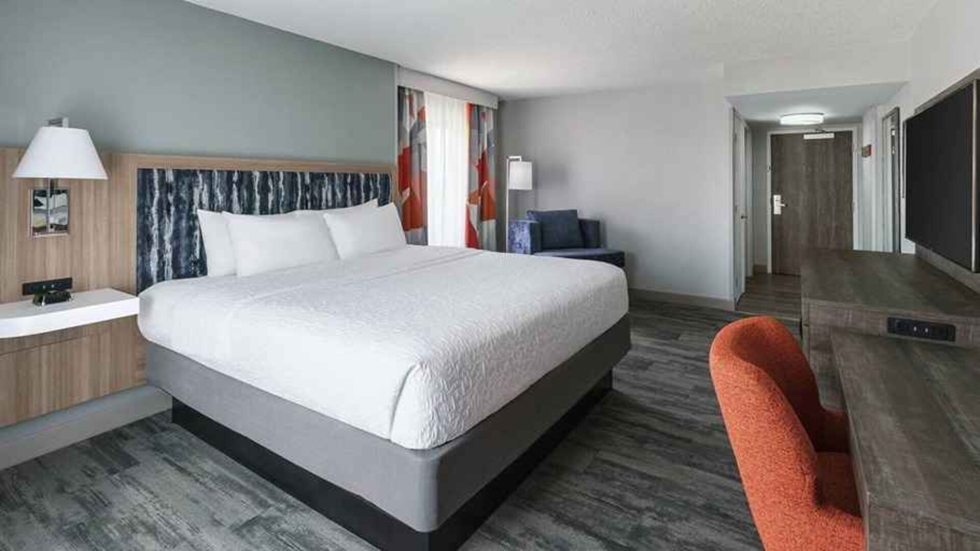 bright-lit king-sized bed in a spacious room with work desk at Hampton Inn & Suites Tampa-Ybor City/Downtown.
