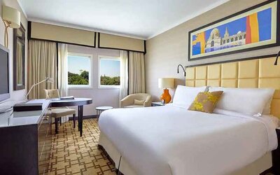 delux king room with TV, desk, chair, and couch at Hilton Cairo Heliopolis.