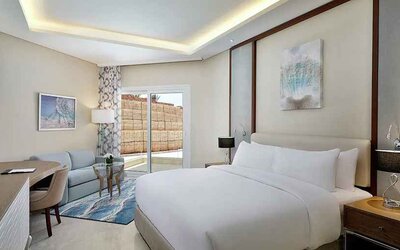 comfortable delux king room with TV, desk, chair, and couch at Hilton Hurghada Plaza.