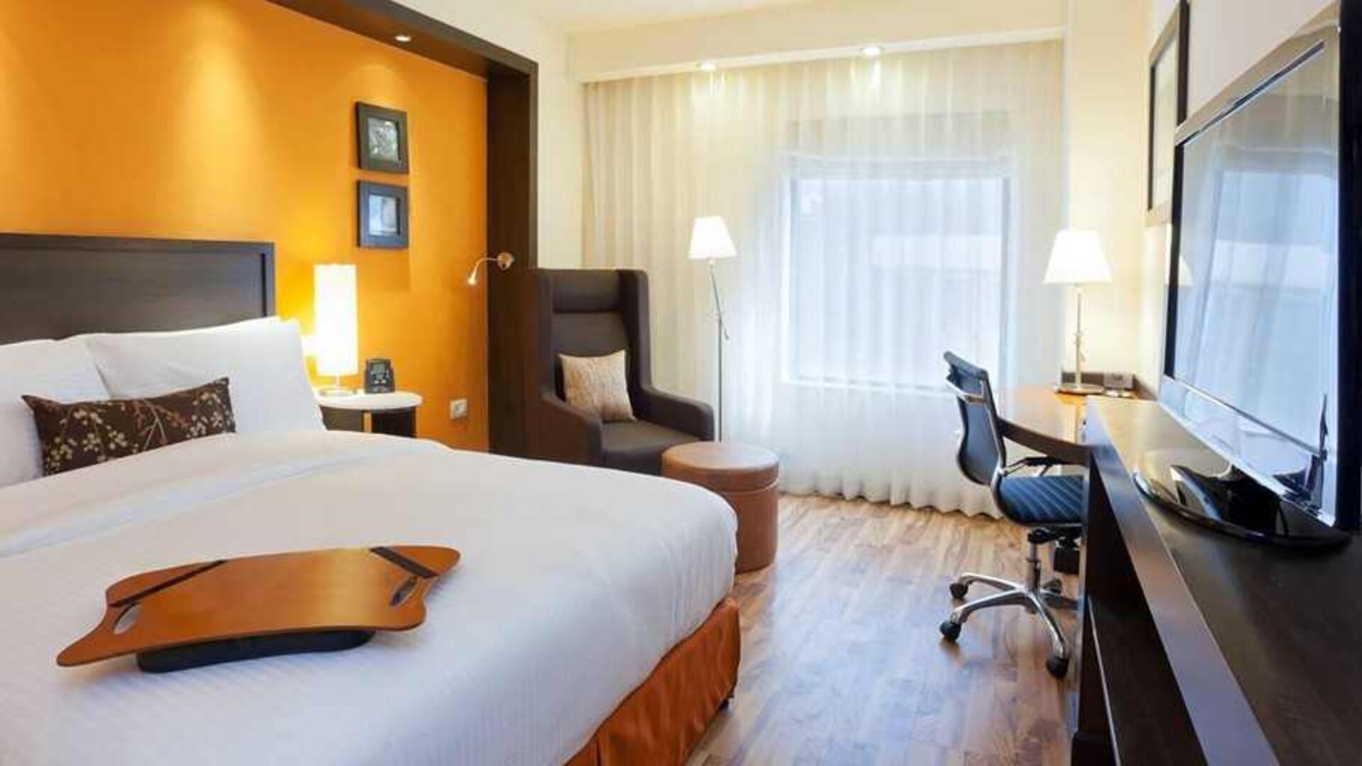 comfortable delux king room with TV, desk, chair, and couch at Hampton by Hilton Vadodara-Alkapuri.