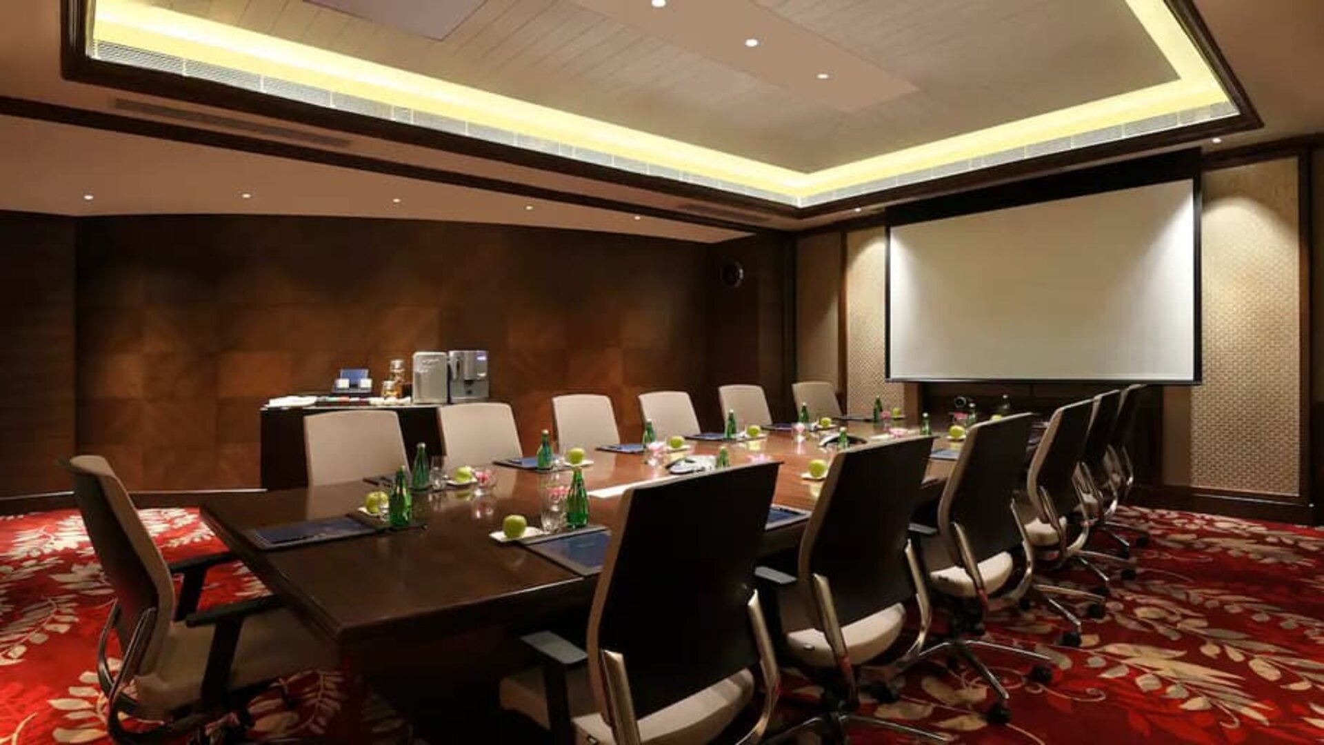 Sleek boardroom with large projection screen, seating for up to 12-15 people.