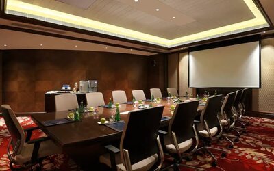 Sleek boardroom with large projection screen, seating for up to 12-15 people.