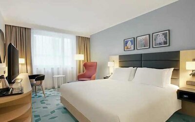 delux king room with TV, desk, chair, and couch at Hilton Garden Inn Budapest City Centre.