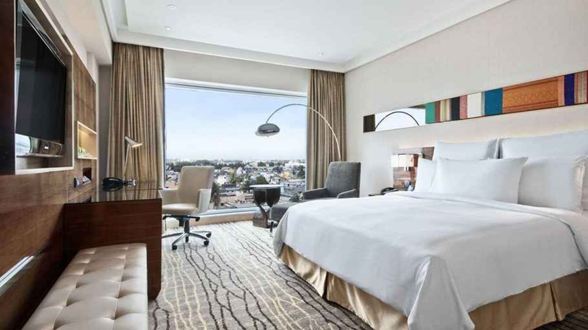 spacious king suite with TV, business desk, lounge area, and city views at Hilton Chennai.