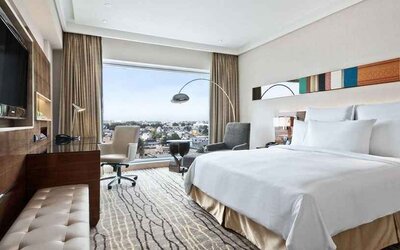 spacious king suite with TV, business desk, lounge area, and city views at Hilton Chennai.