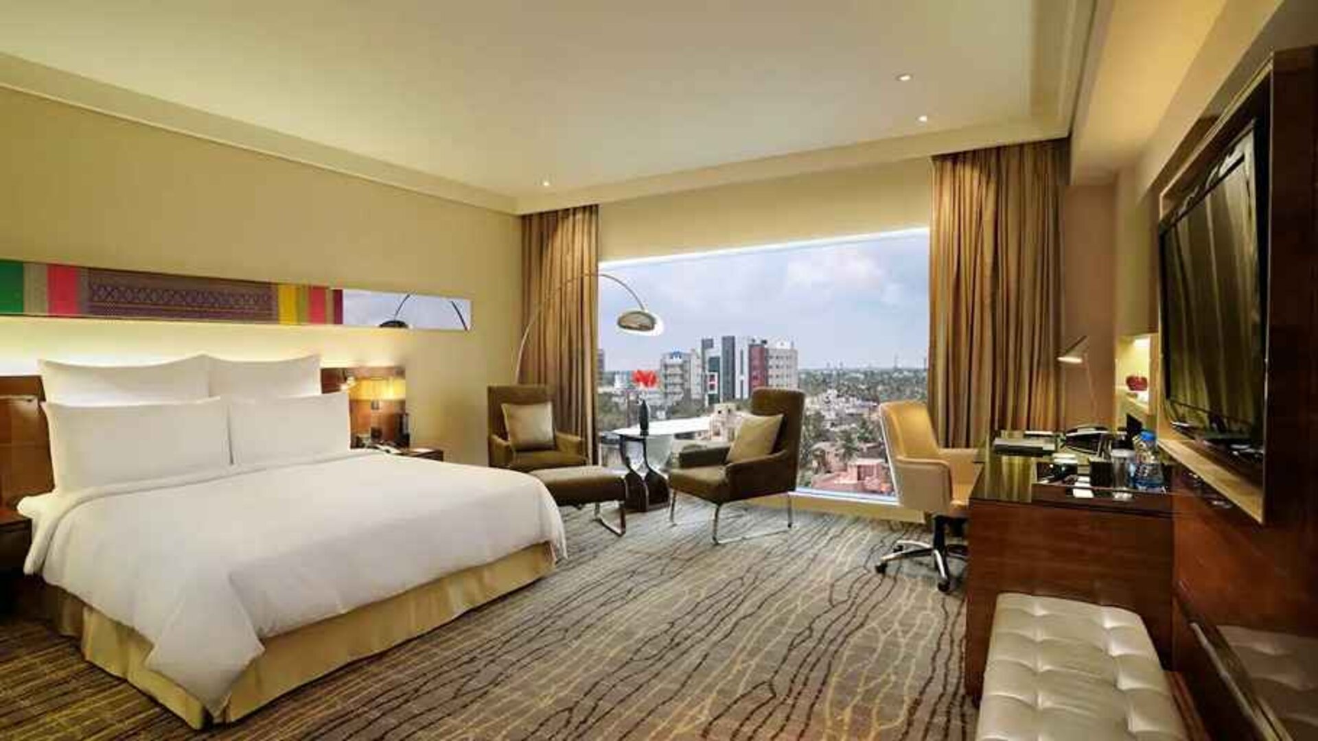 comfortable delux king room with TV, business desk, and lounge area at Hilton Chennai.