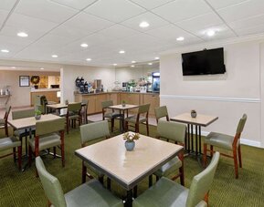 Bright breakfast and dining area with comfortable seating, offering guests a welcoming space to enjoy complimentary breakfast and refreshments at La Quinta Inn & Suites By Wyndham Sawgrass Mills.