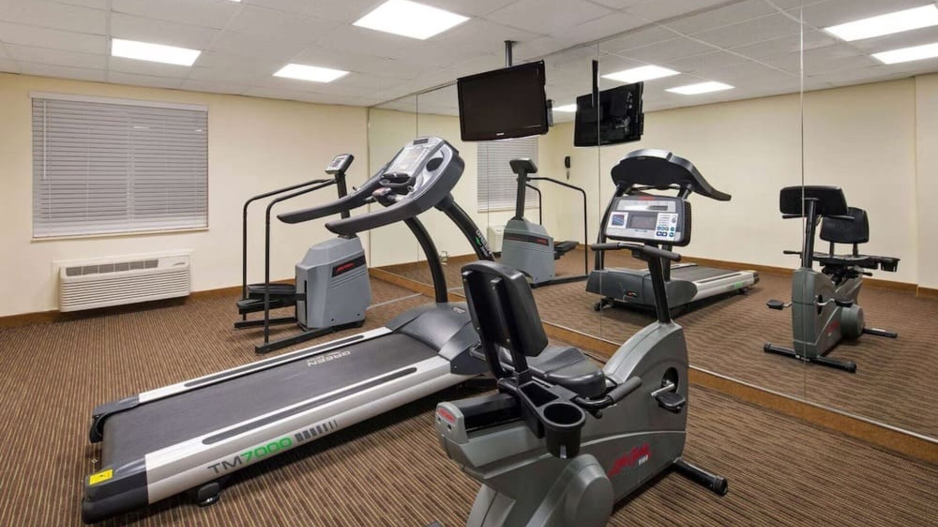 Fitness center equipped with cardio machines and mirrored walls, providing guests with a convenient space to maintain their workout routine during their stay.