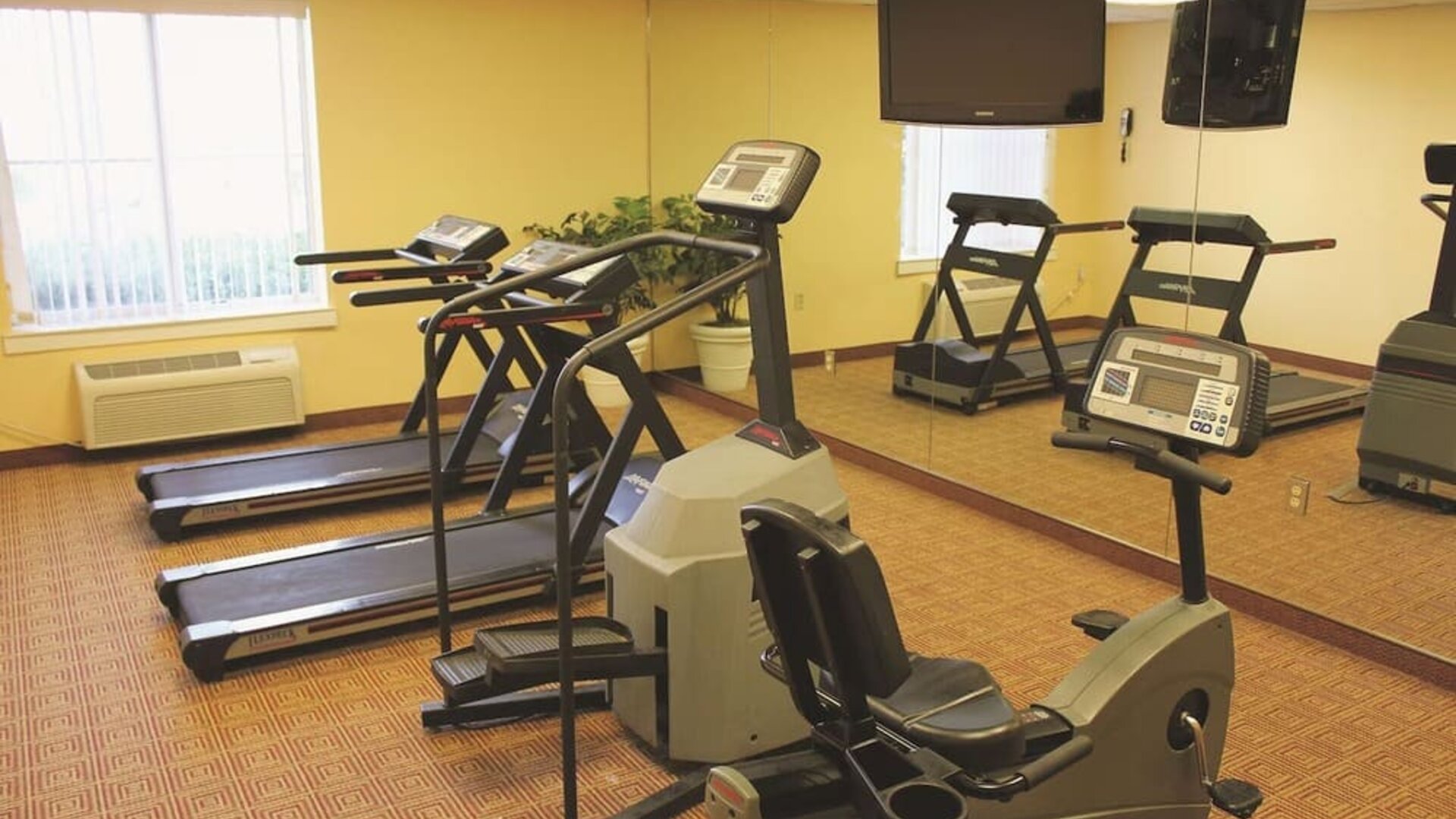 Fitness room with a selection of cardio equipment and workout facilities designed to support guests' health and wellness needs during their stay.