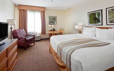 Spacious king room with natural light, comfortable seating, a work area, and modern amenities, offering guests a relaxing space to unwind after a busy day.