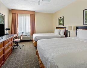 Guest room with two comfortable beds, a work desk, flat-screen TV, and modern amenities, offering a practical and relaxing stay for families, groups, or business travelers at La Quinta Inn & Suites By Wyndham Sawgrass Mills.