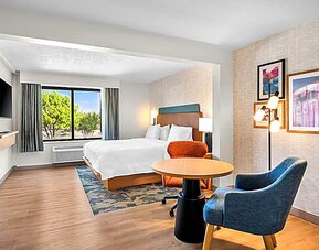Spacious king room with chair and table and TV. 