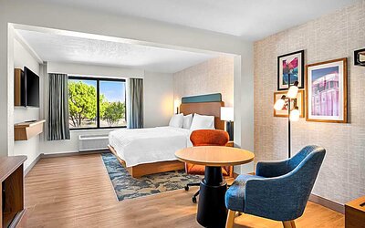 Spacious king room with chair and table and TV. 