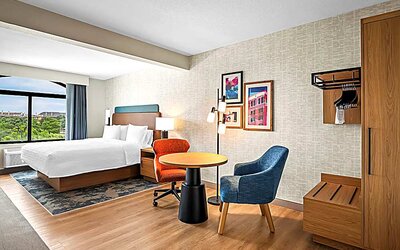 Spacious king room with chair and table and TV. 