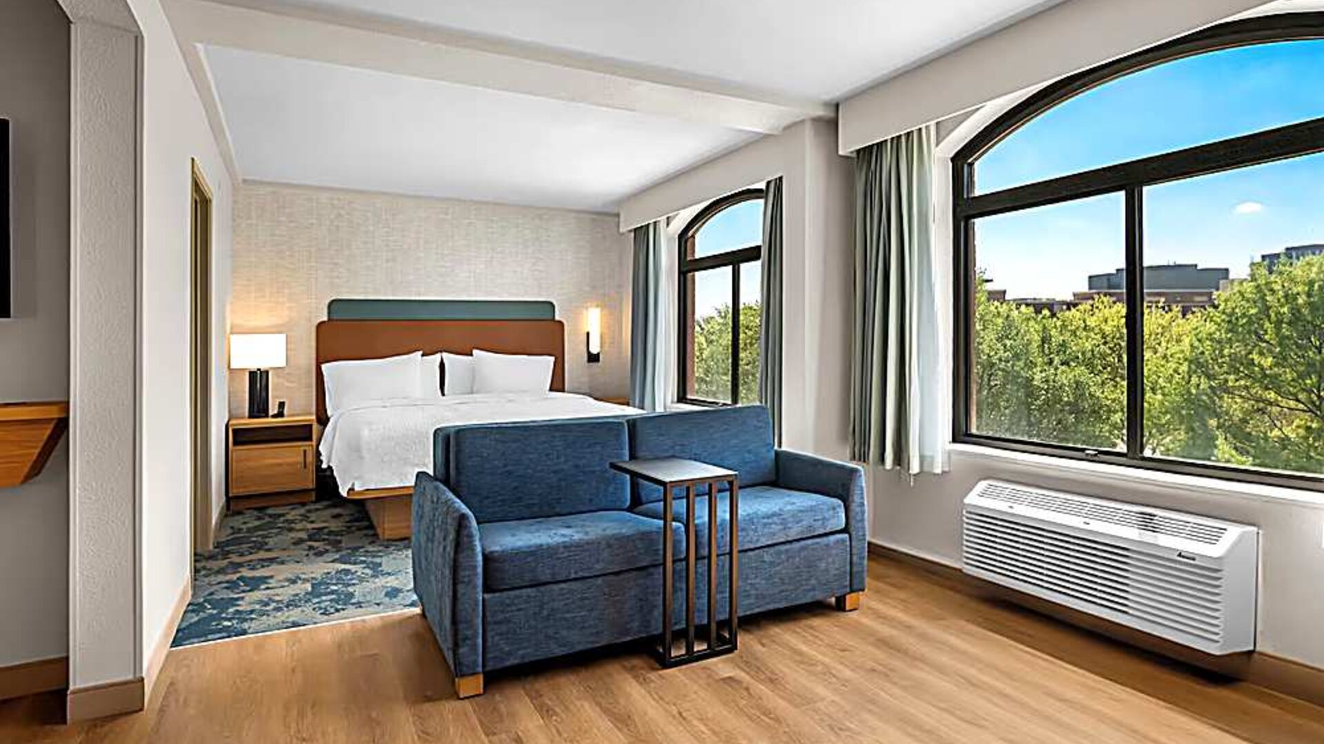 Spacious king room with sofa and large windows Spacious king room with chair and table and TV. 