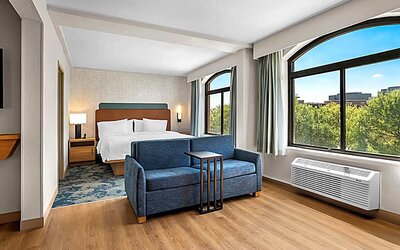 Spacious king room with sofa and large windows Spacious king room with chair and table and TV. 