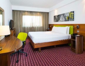 Spacious king room with king bed, natural light, and work desk and chair. 