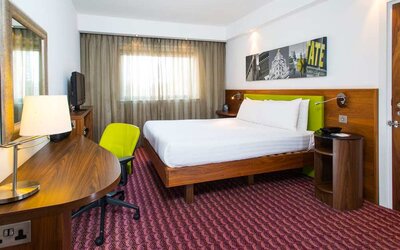 Spacious king room with king bed, natural light, and work desk and chair. 