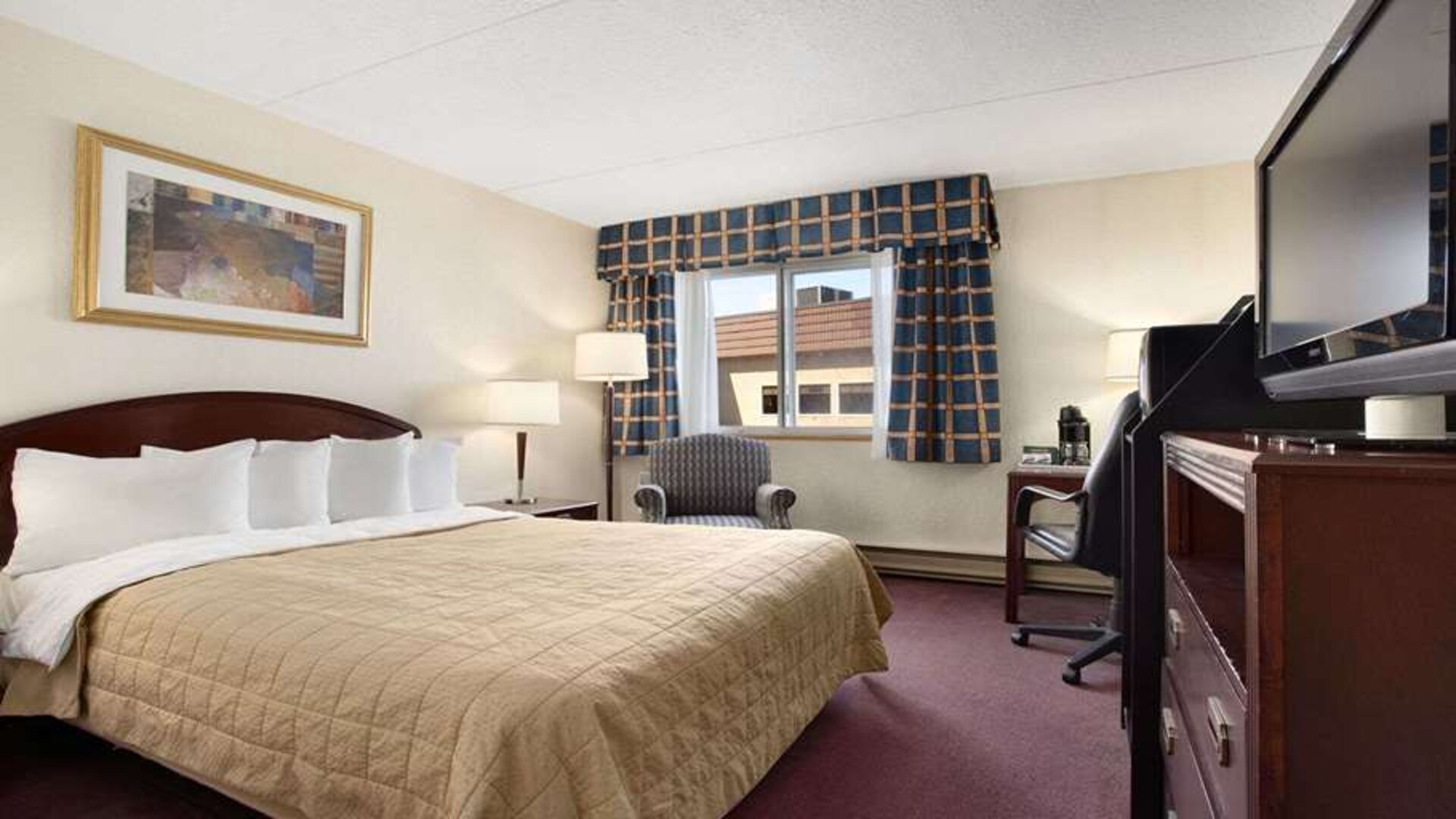 Hotel bedroom with TV screen and desk at Travelodge Ottawa East.
