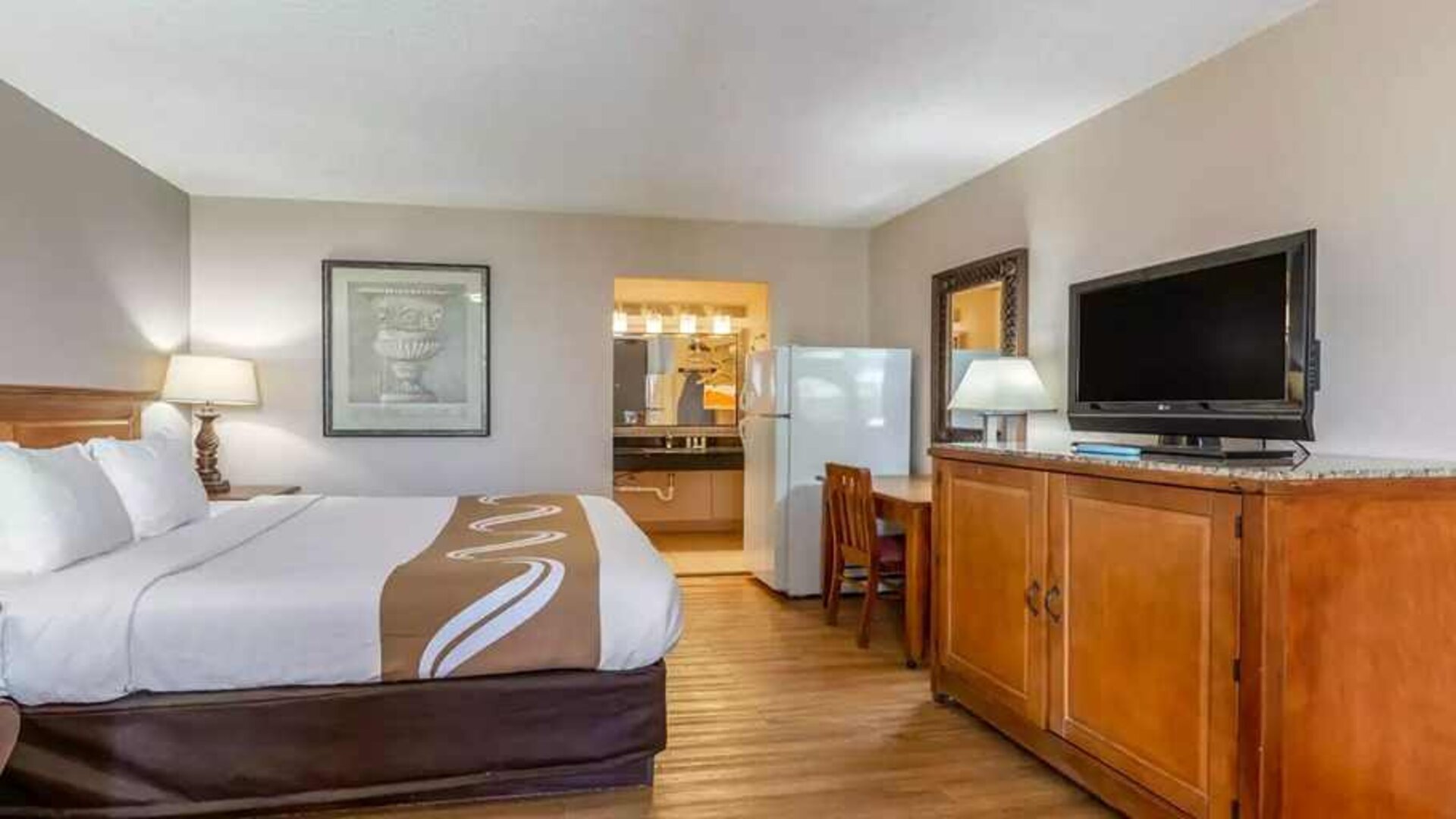 Spacious delux king room with TV, business desk, and fridge at Quality Inn Pasadena.