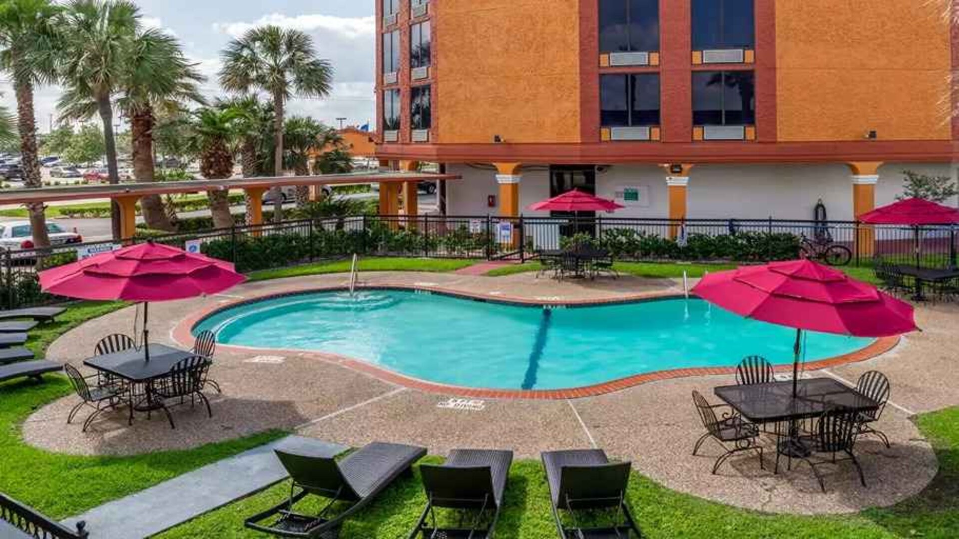 Large outdoor pool with seating area and sun umbrellas at Quality Inn Pasadena.