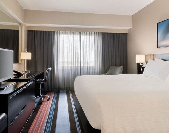 Spacious delux king room with TV, business desk, and couch at Courtyard By Marriott New York JFK Airport.