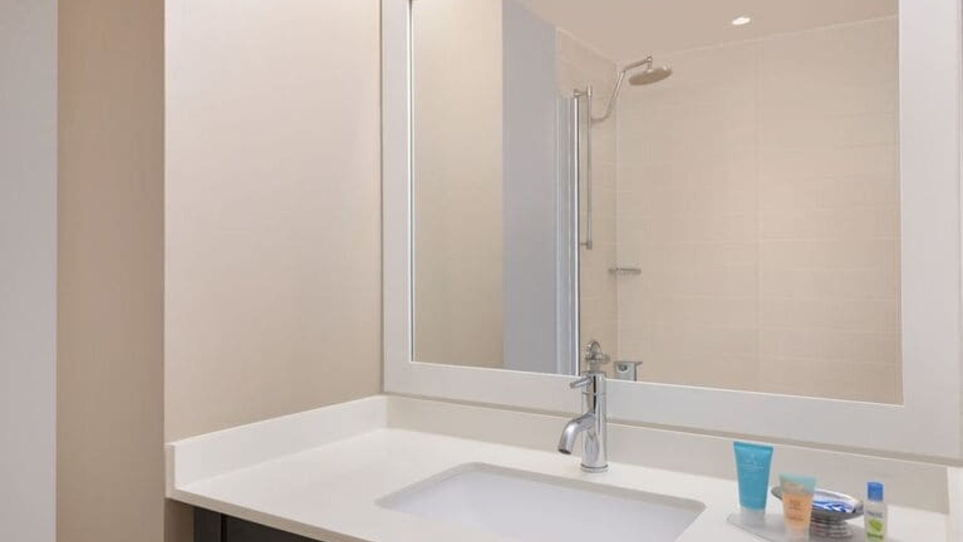 Spacious guest bathroom with shower at Courtyard By Marriott New York JFK Airport.