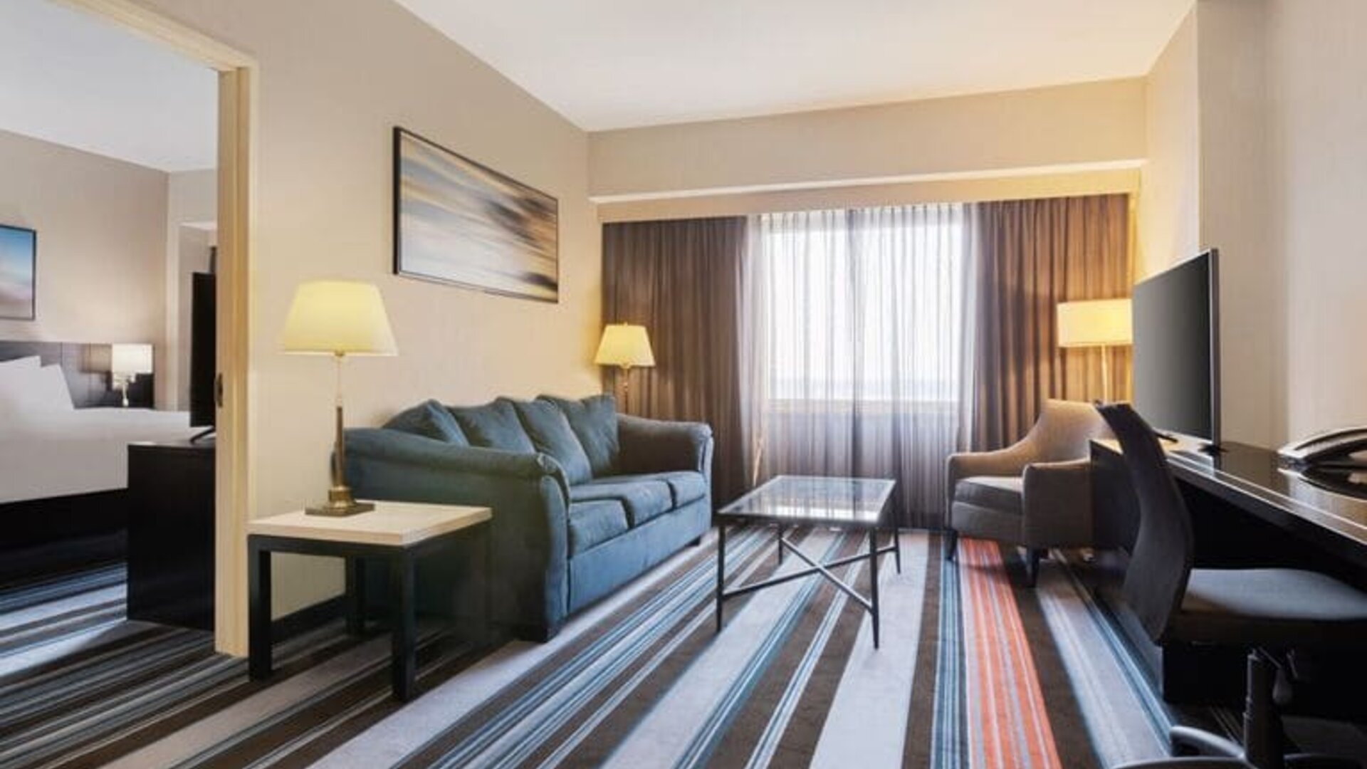 Luxurious king suite with TV, work desk, and couch at Courtyard By Marriott New York JFK Airport.