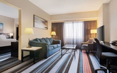 Luxurious king suite with TV, work desk, and couch at Courtyard By Marriott New York JFK Airport.