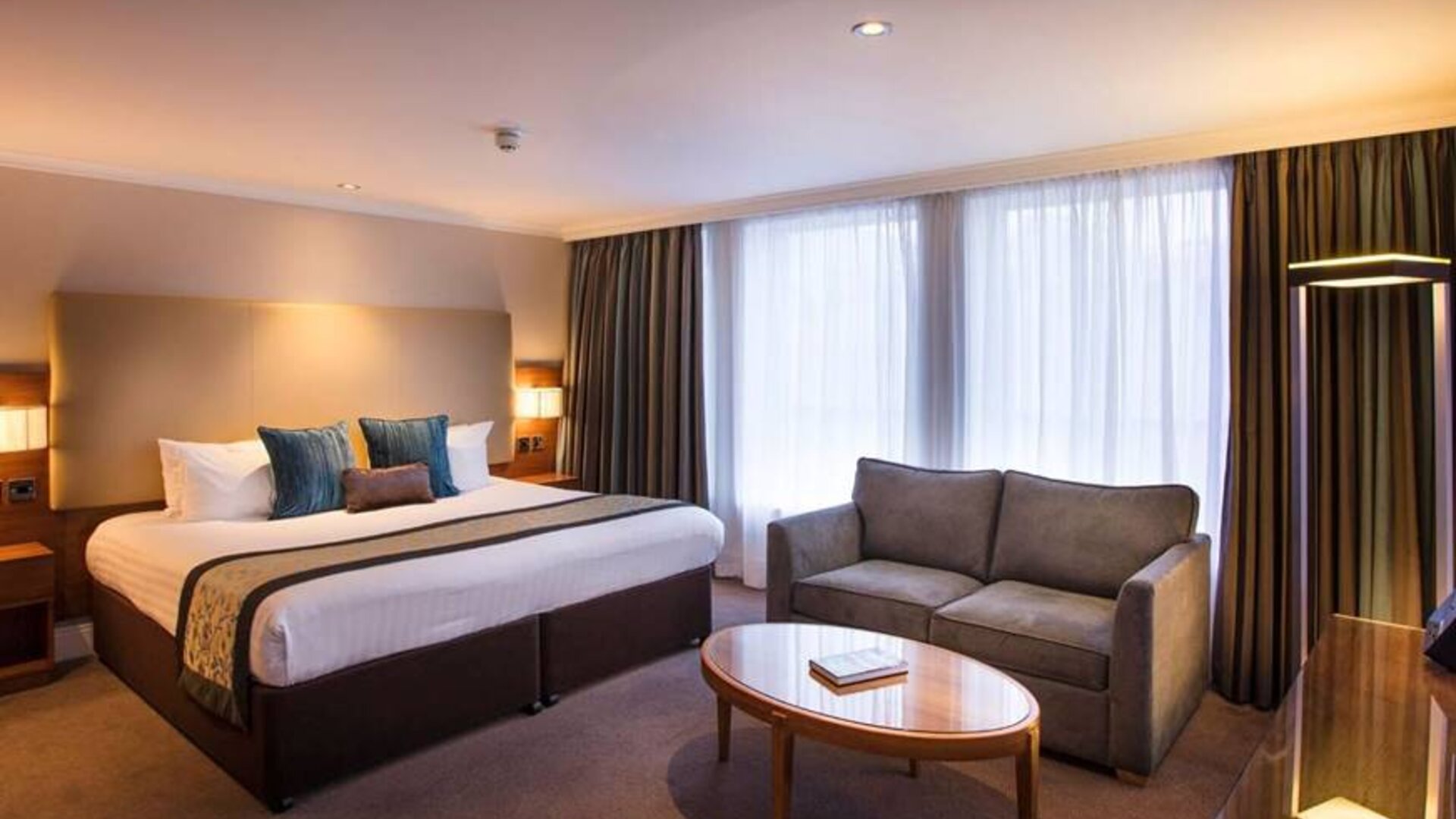 Wide view of the junior suite double room, with small sofa, coffee table, and spacious bed.