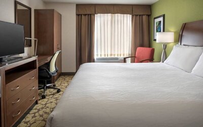 Guest room in the Hilton Garden Inn Chicago Downtown Riverwalk, including large bed, window, and desk and chair for working.