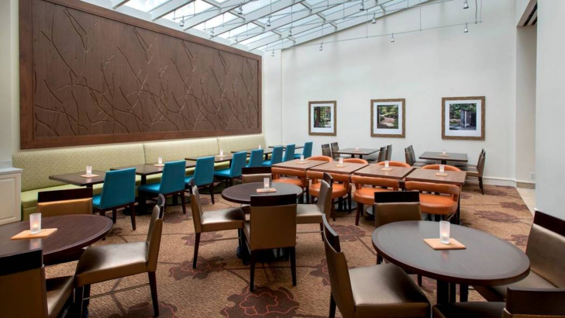 The hotel restaurant offers on-site dining, with varying table sizes and a bright and airy environment.