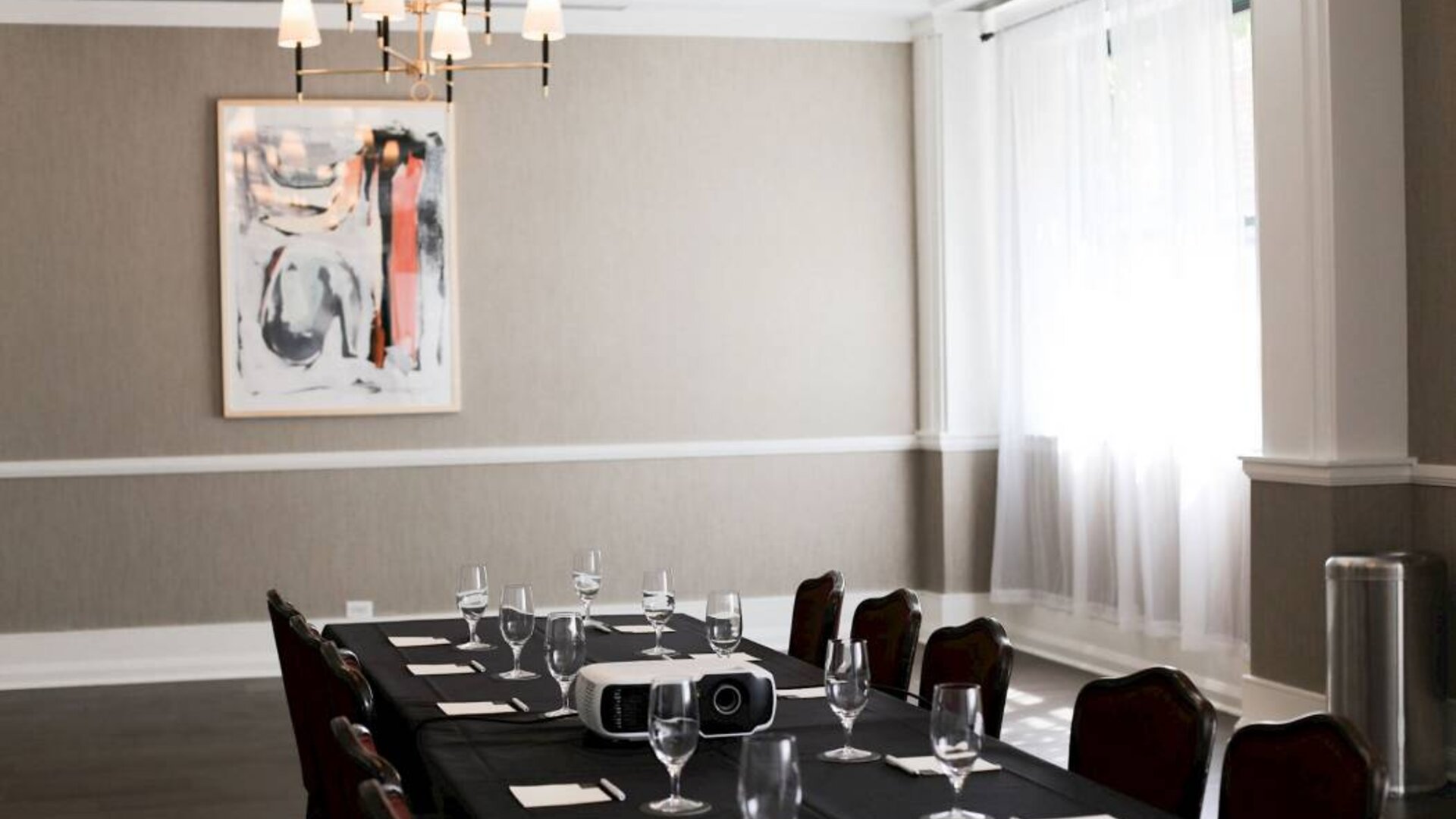 One of the hotel’s meeting room facilities, with long table, surrounding chairs, art on the wall, and large window.