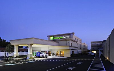 The exterior of the hotel, which provides shade/cover from the rain for the entranceway, and space for parking.