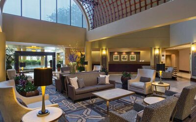 Lounge in the Sheraton Houston Brookhollow Hotel lobby, with array of comfy chairs and sofas, plus small tables.