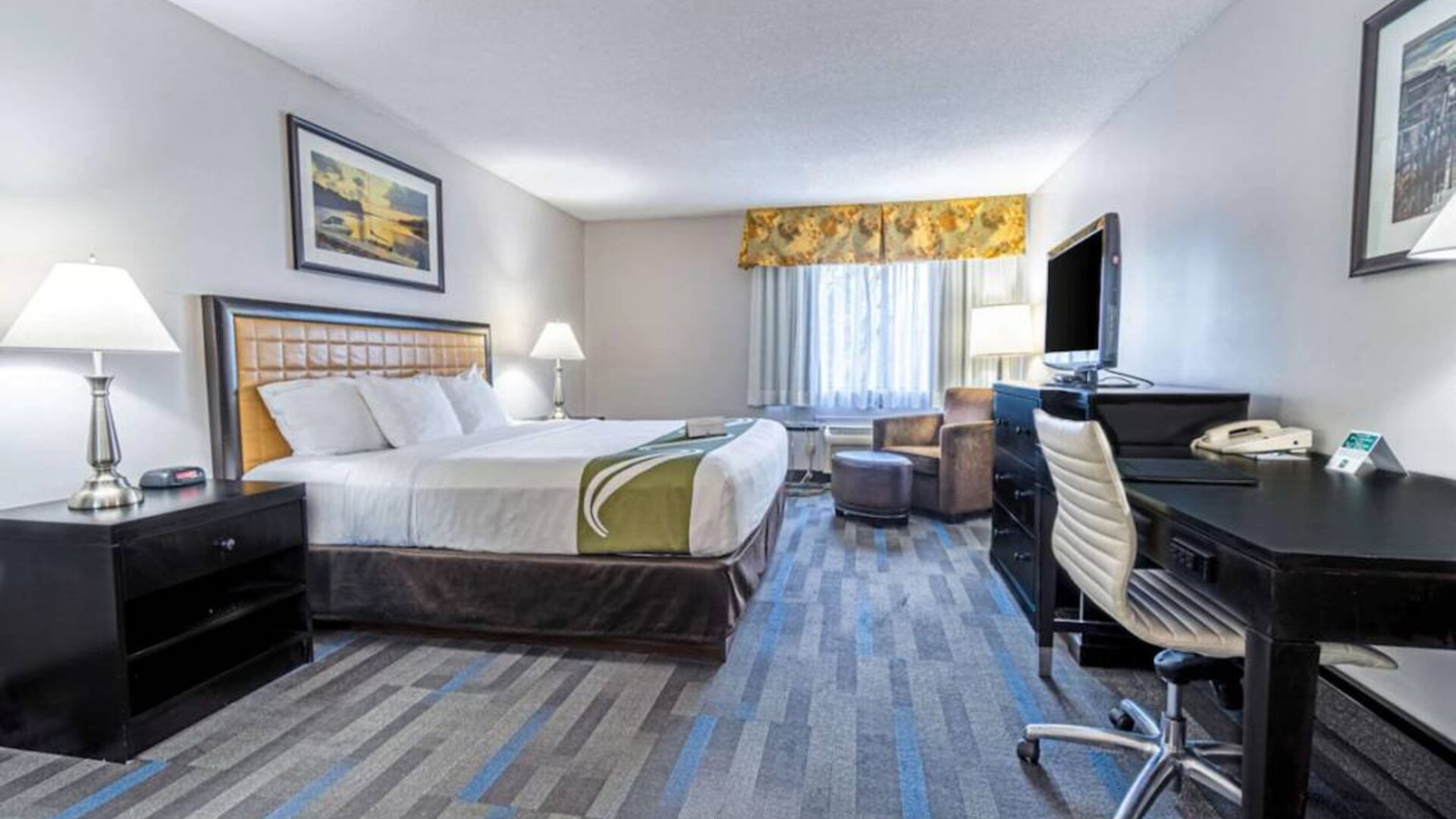 Double bed guest room in the Quality Inn Halifax Airport, furnished with large TV and a workspace desk and chair.