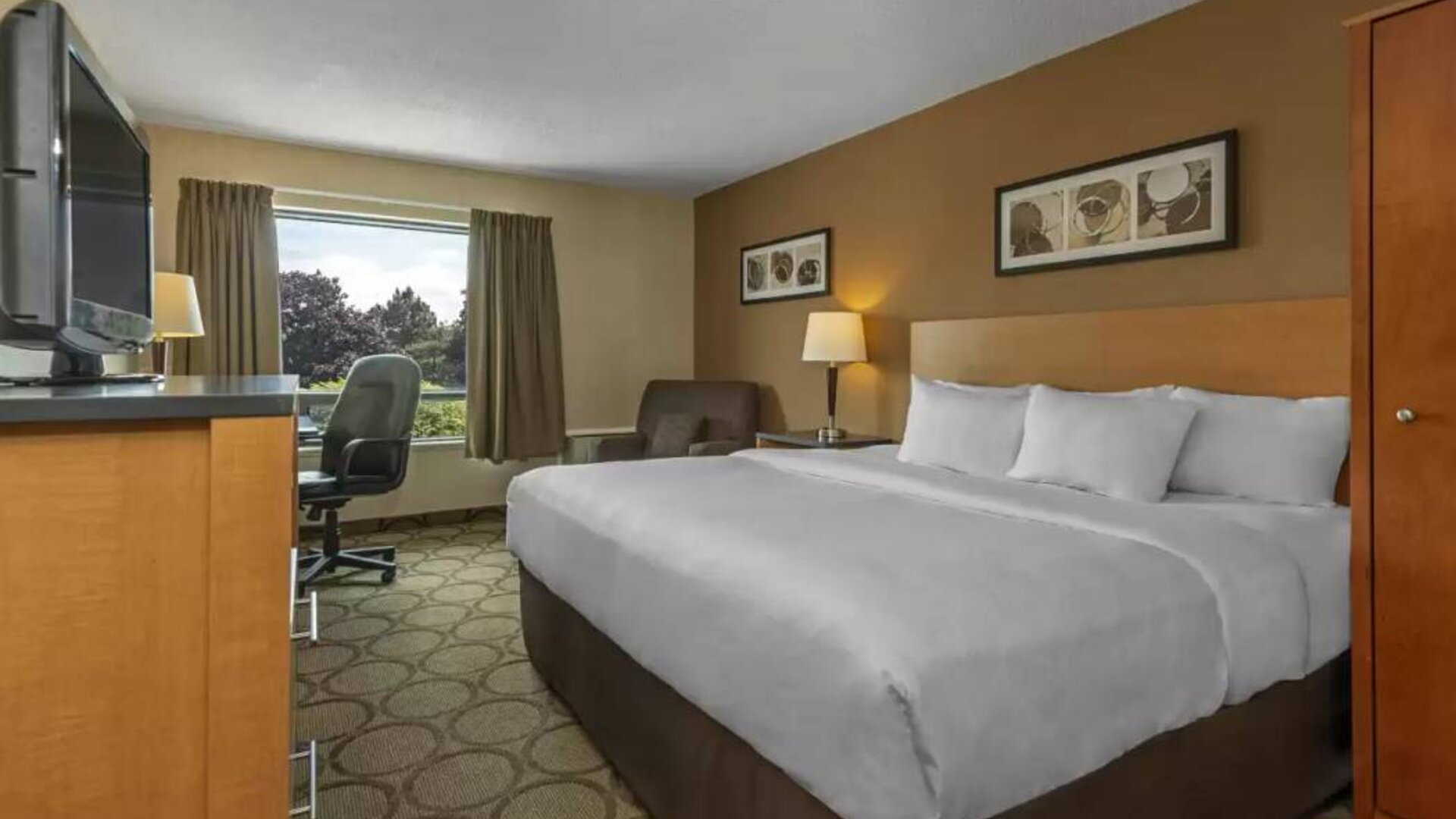 Double bed guest room in Comfort Inn Edmonton West, with nearby chair and TV.