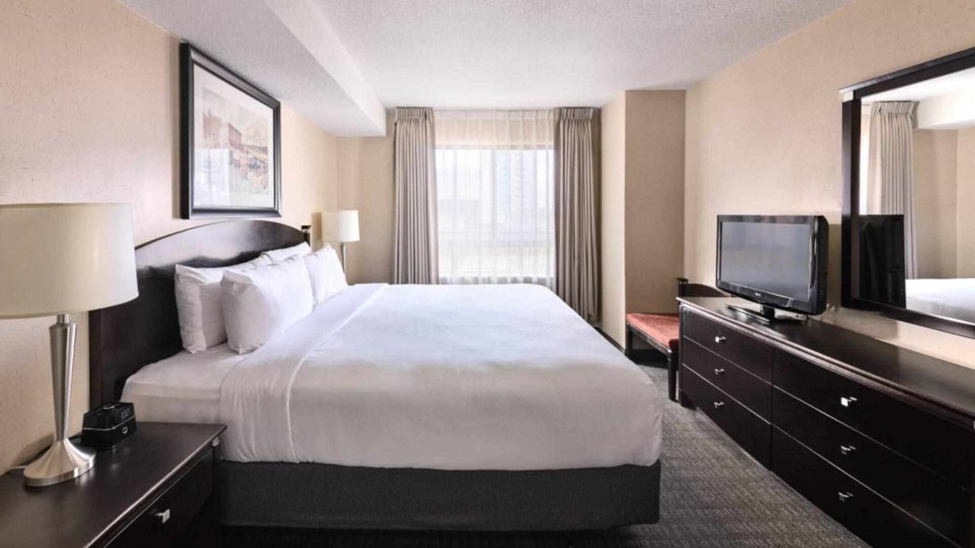 Double bed guest room in Les Suites Hotel Ottawa, with large window and TV.