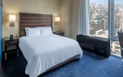 Guest room at the Hilton Fashion District, with double bed and view of the city.