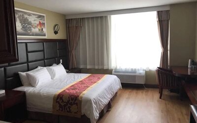 Queens Hotel guest room, including table, chair, window, and large double bed.