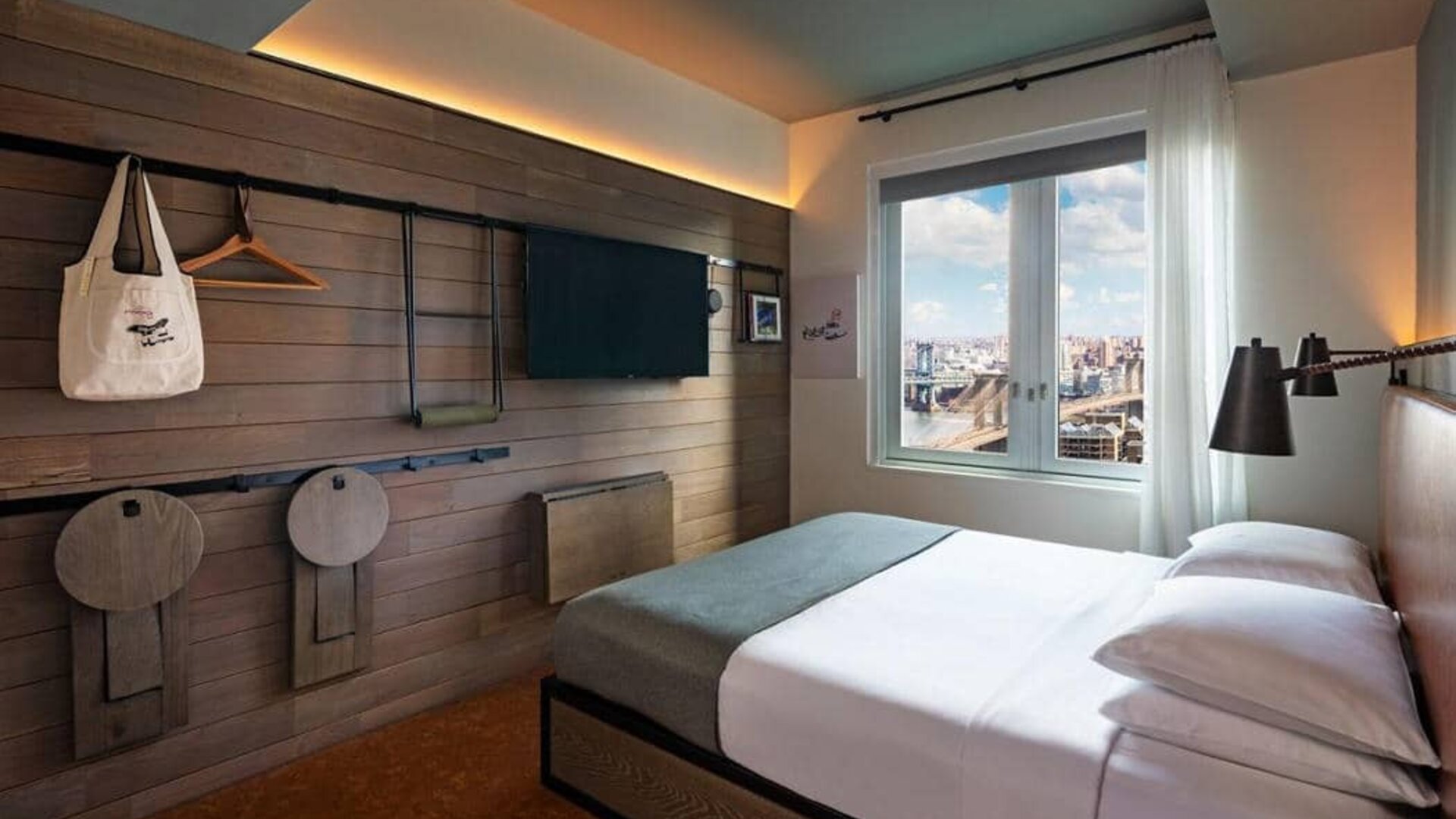 Double bed guest room in the Moxy NYC Downtown, with large TV and window.