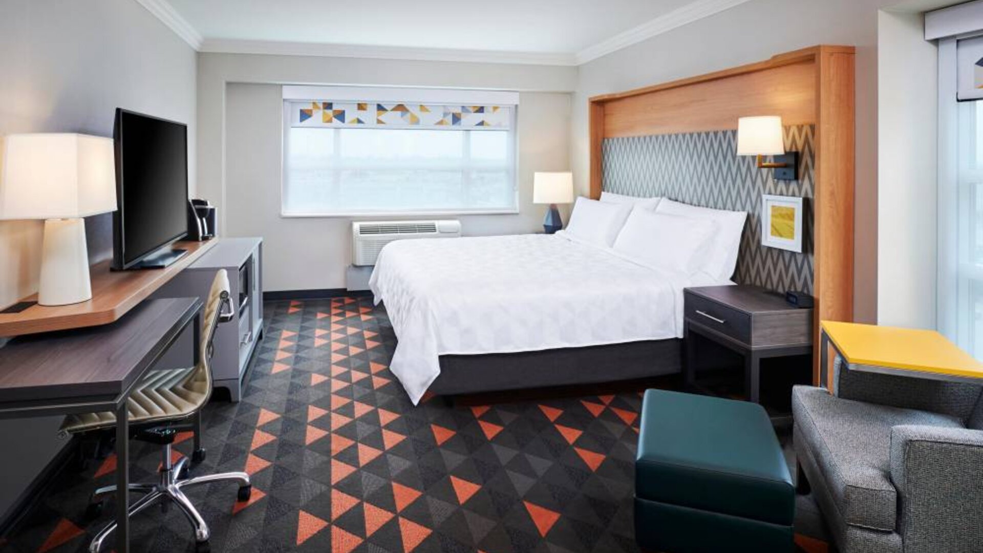 Guest room in Holiday Inn & Suites Oakville At Bronte, with double bed, chair and desk for working, and TV.