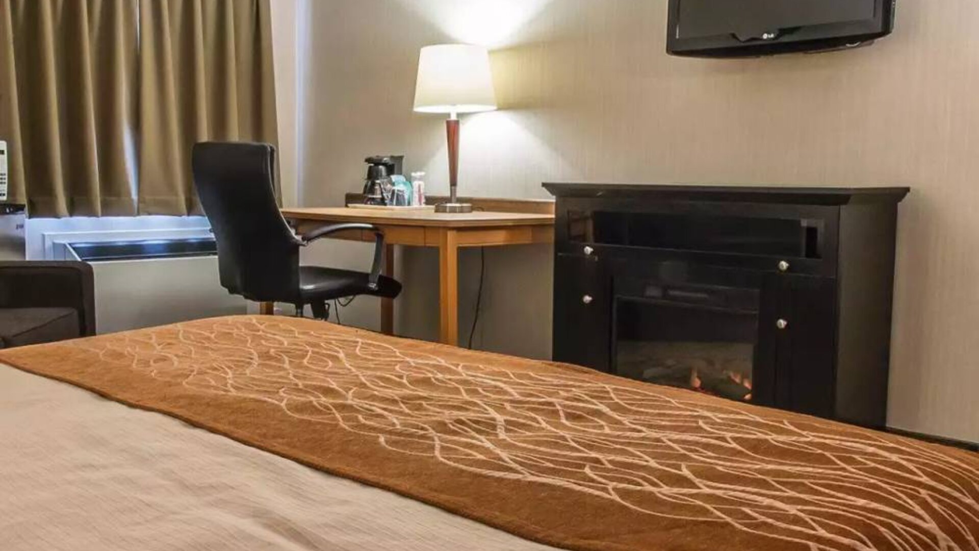 Guest room workspace in Comfort Inn Brandon, with a cozy fireplace beside the desk and chair.
