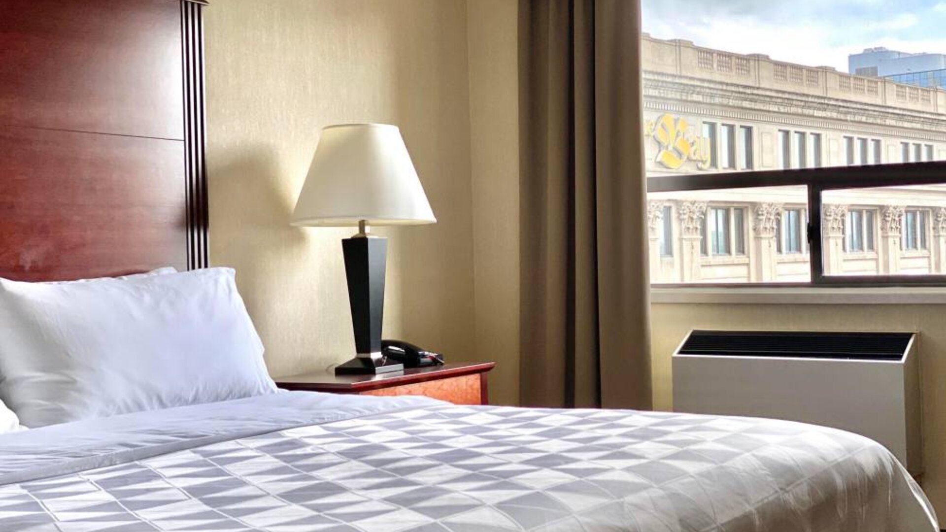 Guest room in Holiday Inn Winnipeg Downtown, with bedside lamp and window.