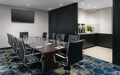 Hotel meeting room, with ten leather chairs surrounding a long table, and coffee-making facilities.