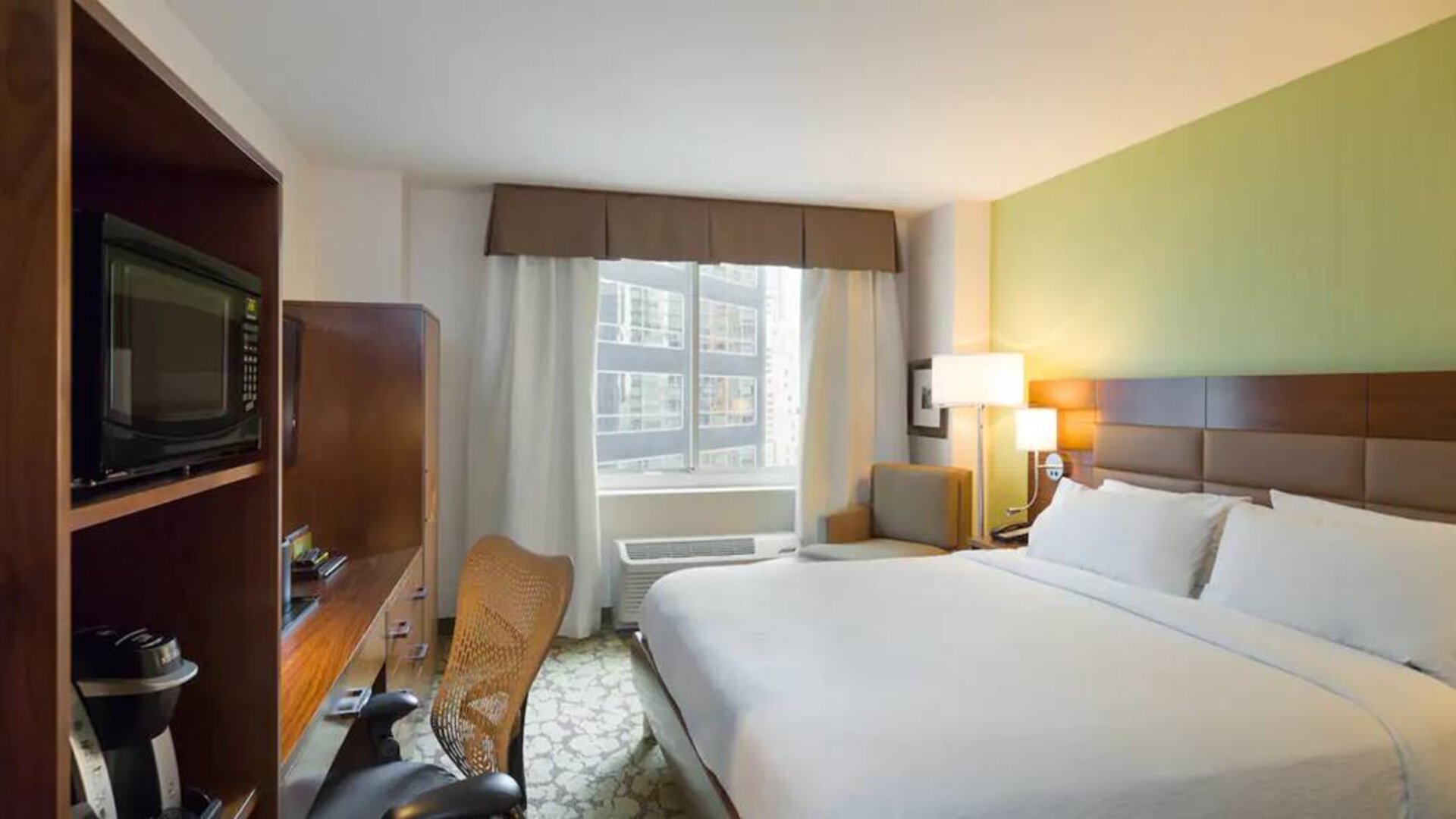Hilton Garden Inn Midtown East guest room featuring large bed, big windows, and workspace chair and desk.
