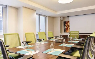 A meeting room in the Hilton Garden Inn Midtown East, with long wooden table and space for ten attendees.