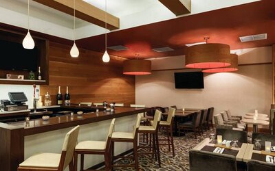 The Hilton Garden Inn Midtown East’s restaurant and bar, with tall bar stools, and tables for dining.