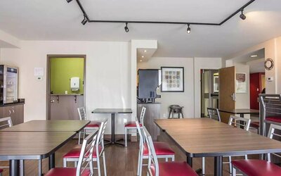 The hotel breakfast area has a hard floor and tables for two to four diners.
