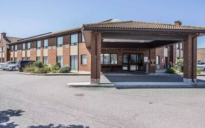 The entrance to Comfort Inn Gatineau is under cover, with nearby greenery and ample parking.